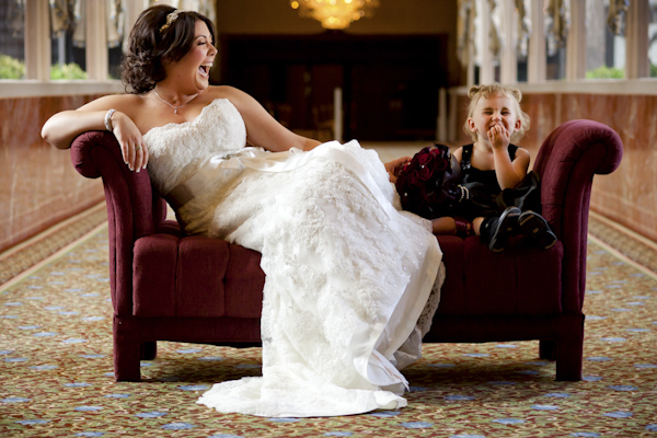 bride and little girl sitting on couch and laughing - wedding photo by top Denver based wedding photographer Hardy Klahold